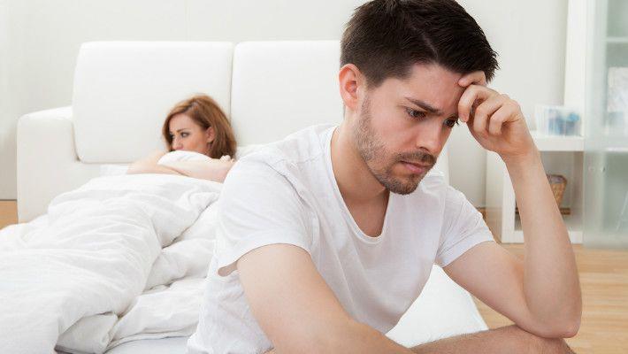 גבר יושב על מיטה מתוסכל כי סובל מבעיות זקפה