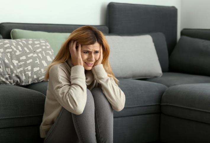 אישה יושבת מכווצת בעיצומו של התקף חרדה 